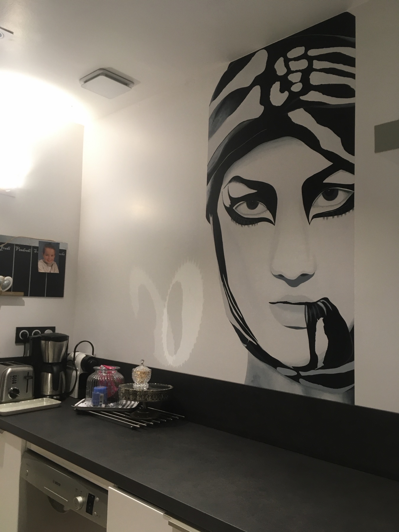 Visage peint noir et blanc installé dans une cuisine