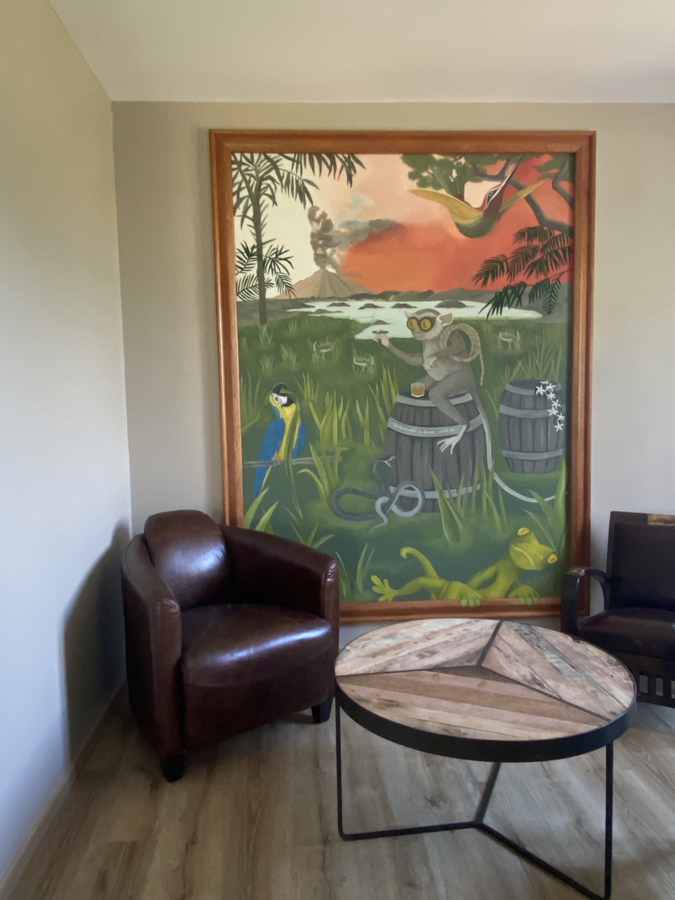 Peinture tropicale encadrée dans un salon, fauteuils club